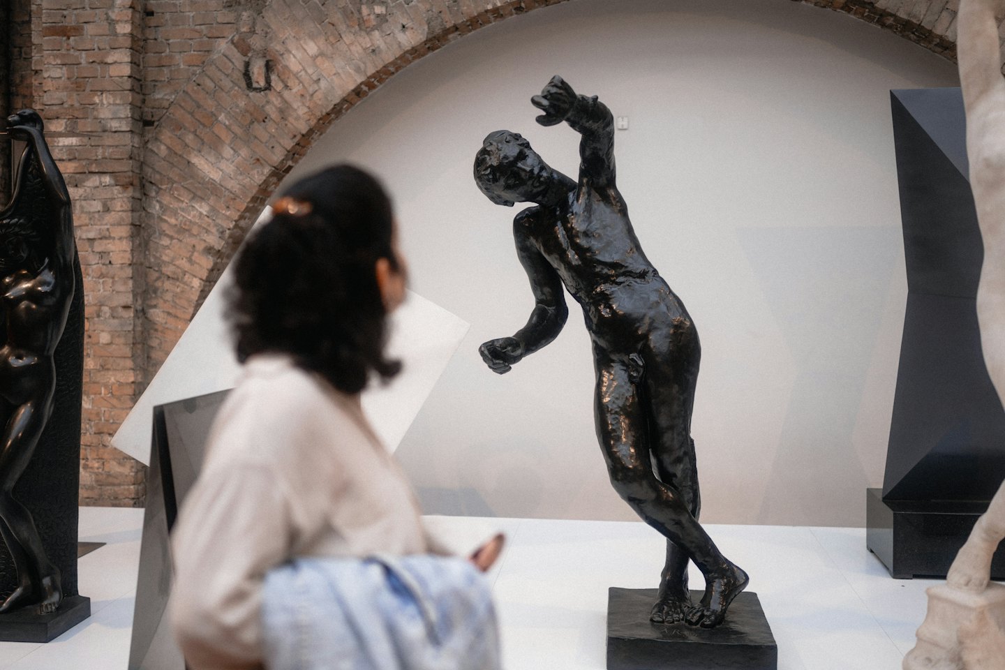 Besucher einer Galerie betrachtet eine Bronzestatue einer nackten Frau.
